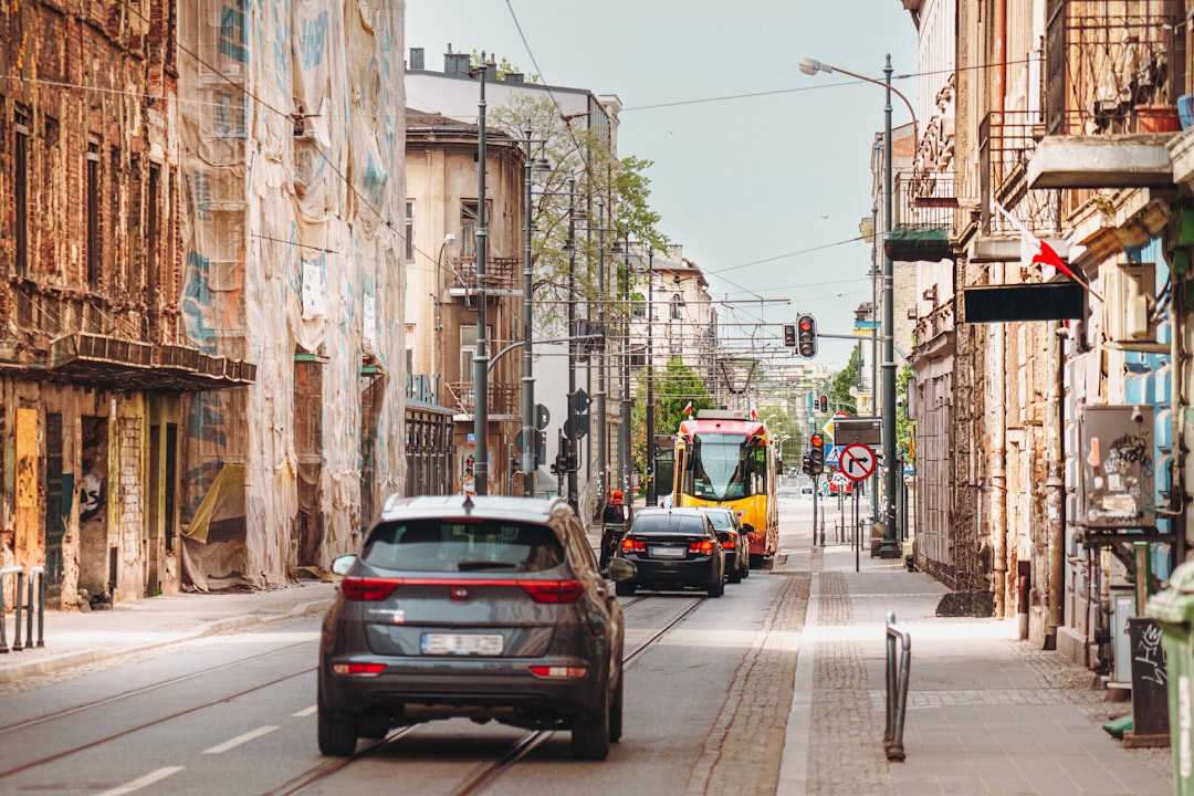 Cars and a tram travel down a city street.